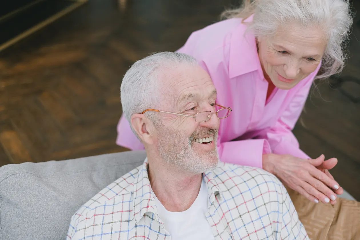 A retired couple smiling together at home while planning their retirement finances